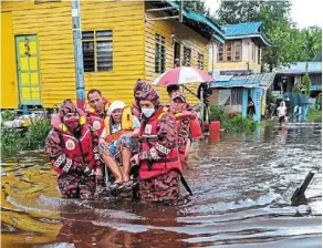  ?? — Filepic ?? Fire and rescue department personnel helping an elderly woman to evacuate her home in Kampung seduan, sibu in sarawak after it was hit by flash floods on Jan 12.