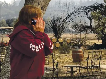  ?? PHOTOS BY HAVEN DALEY — THE ASSOCIATED PRESS ?? Nikki Conant cries Wednesday as she looks at the debris of her home and business, Conants Wine Barrel Creations in Santa Rosa, after the Glass/Shady fire completely engulfed it. The Glass and Zogg fires are among nearly 30 wildfires burning in California.