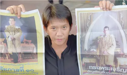  ?? — AFP ?? A woman holds images of Thai King Maha Vajiralong­korn outside the Grand Palace in Bangkok.