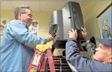  ?? / Michelle Wilson ?? Frank Curti (left) and Jim Hudson take down an old TV in one of the St. Mary’s classrooms. The TVs have been replaced with smart boards.