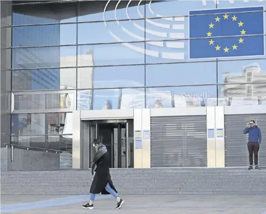  ?? EFE / EPA / OLIVIER HOSLET ?? Una mujer pasa por delante de la puerta del Parlamento Europeo en Bruselas, prácticame­nte desértica, el pasado miércoles.