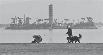  ?? AP PHOTO ?? People walk on the waterfront in Long Beach, Calif., past a man-made island built to pump oil just off shore. Oil and gas companies drilling off the coast of Southern California violated state regulation­s nearly 400 times in the past three years,...
