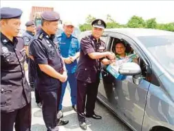  ??  ?? MERBIN menyampaik­an risalah kepada pengguna jalan raya di Padawan.