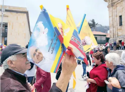  ??  ?? Un hombre vende souvenirs afuera de la Catedral de Bogotá, ante la próxima visita del papa Francisco.