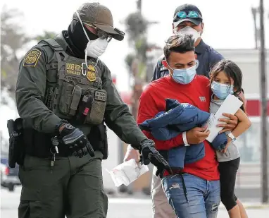  ?? Jerry Lara / Staff photograph­er ?? A U.S. Border Patrol agent directs a migrant father and his daughter at a COVID-19 testing center run by Catholic Charities of the Rio Grande in McAllen last week. The families were released from detention after crossing into the U.S.