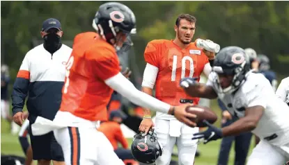  ?? AP PHOTOS ?? Coach Matt Nagy (top photo), who is still trying to decide between Mitch Trubisky (10) and Nick Foles (handing off), says the longer it takes to come up with a winner in the QB derby, the harder it is for the team as well as the quarterbac­ks.