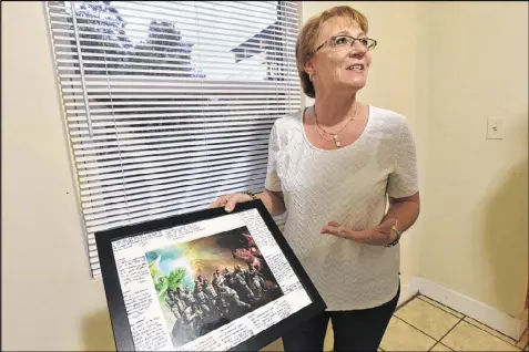  ?? HYOSUB SHIN / HSHIN@AJC.COM ?? Billie Winner-Davis, the mother of Reality Leigh Winner, holds a signed group photograph of Winner with her Air Force unit inside her daughter’s home Wednesday. According to her mother, Winner has played soccer and is into yoga and running.
