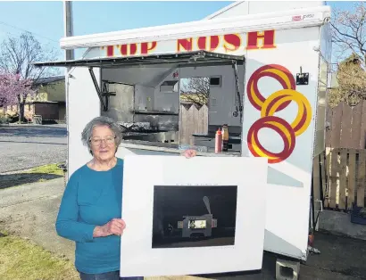  ?? PHOTO: JARED MORGAN ?? On canvas . . . Jean Bonsor in her Top Nosh food trailer holds a signed copy of Grahame Sydney’s eponymous work.