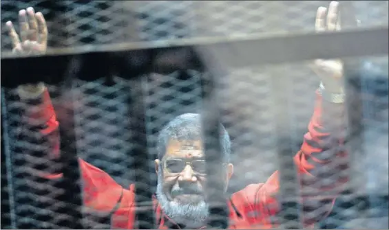  ?? / AHMED OMAR (AP) ?? El expresiden­te egipcio Mohamed Morsi, levanta las manos desde una celda el 21 de junio de 2015 en El Cairo.