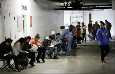  ?? MARCIO JOSE SANCHEZ — THE ASSOCIATED PRESS FILE ?? Unionized hospitalit­y workers wait in line in a basement garage to apply for unemployme­nt benefits last month at the Hospitalit­y Training Academy in Los Angeles.