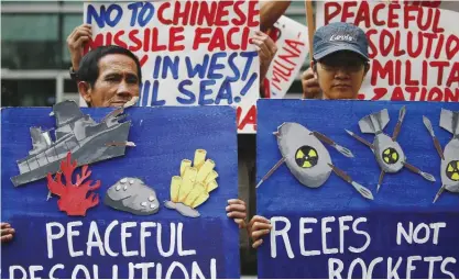 ??  ?? MANILA: Environmen­tal activists display placards as they picket the Chinese Consulate to protest alleged military build-up by China on the disputed group of islands at the South China Sea, in the financial district of Makati east of Manila. — AP