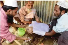  ??  ?? Myanmar Rohingya refugees wash the body of six-month-old Alam before his burial in a refugee camp in Teknaf, in Bangladesh’s Cox’s Bazar district yesterday. — AFP