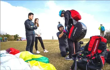  ??  ?? (From left) Yes Chan and Carmen Li watch as university lecturer and youth counsellor Giovanni Lam prepares Keith Yung before they paraglide in tandem from Ma On Shan peak in Hong Kong. — AFP photos