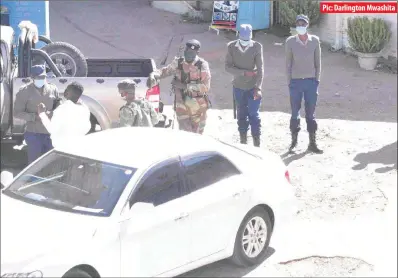  ??  ?? Police officers and soldiers interrogat­e a man (in white jersey) at a car wash area near Amtec Building in Bulawayo yesterday