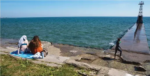  ?? PAT NABONG/SUN-TIMES ?? People sit under the sun near Foster Beach in Edgewater this month. Because of unusually hot weather, Chicago just recorded its longest streak of high-pollution days in more than a decade.