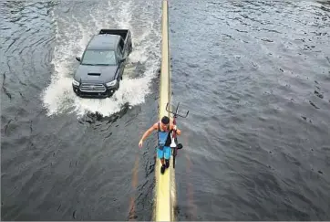  ?? Ricardo Arduengo AFP/Getty Images ?? A MAN walks on a divider of a flooded highway in the aftermath of Hurricane Maria in San Juan.