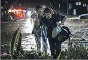  ?? Michael Owen Baker For The Times ?? ROSA GALLARDO, left, and Connie Duarte cross a flooded Montecito street Monday after work.