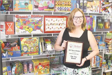  ?? Chris Bosak / Hearst Connecticu­t Media ?? Kimberly Ramsey of The Toy Room in Bethel stands in front of board games at her store and holds her plaque for being named the 2017 Business of the Year by the Bethel Chamber of Commerce.