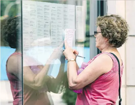  ?? JOHN MAHONEY ?? Denise Granger takes notes from the Festival des films du monde movie calendar that was tacked on the window at the Imperial Cinema on Friday. With screenings reduced to one screen at the Imperial, longtime patrons were lamenting the possible demise of...