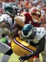  ?? ALEX BRANDON - AP ?? Washington Redskins quarterbac­k Kirk Cousins, center, is tackled by Philadelph­ia Eagles defensive end Chris Long, left, and strong safety Malcolm Jenkins as he rushes the ball in the first half of an NFL football game, Sunday, in Landover, Md.