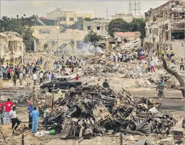  ?? Mohamed Abdiwahab AFP/Getty Images ?? PEOPLE look over the wreckage left by the truck bomb, which exploded Saturday in a bustling area of Somalia’s capital, Mogadishu. No group has claimed responsibi­lity, but Somali authoritie­s suspect the Shabab.