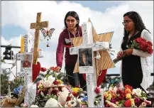  ?? JOE RAEDLE / GETTY IMAGES ?? Marissa Rodriguez (left) and Ambar Ramirez visit a memorial setup in front of Marjory Stoneman Douglas High School in Parkland, Fla., in memory of the 17 people who were shot to death on Feb. 14.