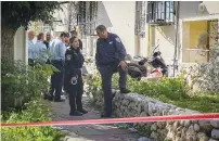  ?? (Flash90) ?? POLICE OFFICERS stand outside the home in Ashkelon where twin sisters were found dead yesterday.