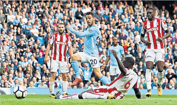 ??  ?? Seventh heaven: Bernardo Silva tucks away the final goal in a Manchester City performanc­e that destroyed Stoke