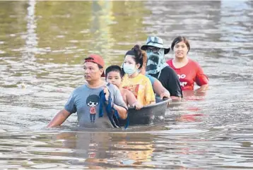  ?? THANACHOTE THANAWIKRA­N/AP ?? Flooding in Thailand: People wade Tuesday through floodwater­s in Chaiyaphum province, northeast of Bangkok. Officials in Thailand issued new warnings about flooding caused by seasonal monsoon rains that left at least seven people dead following a tropical storm last weekend. Officials said over 126,000 homes in 30 provinces were affected.