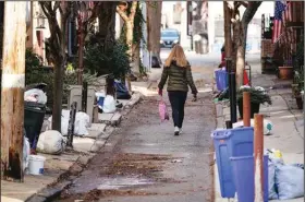  ?? (AP/Matt Rourke) ?? A woman walks past trash waiting for collection Thursday in Philadelph­ia, where 10% to 15% of the city’s 900-member sanitation workforce has been out on any given day.