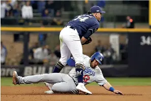  ?? AP Photo/Jeff Roberson ?? ■ Milwaukee Brewers third baseman Hernan Perez (14) tags Los Angeles Dodgers' Max Muncy (13) out and turns to a double play during the eighth inning of Game 2 of the National League Championsh­ip Series baseball game Saturday in Milwaukee.