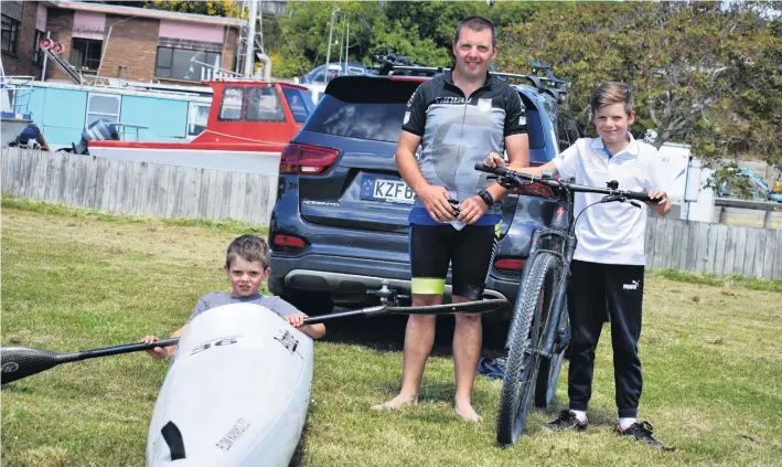  ?? PHOTO: WAYNE PARSONS ?? Inspiring dad . . . Kathmandu Coast to Coast bound Craig Lay prepares his gear with sons Rhys (8) trying out the kayak and Jayden (10) trying the bike out for size.