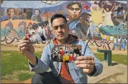  ?? AP/REED SAXON ?? Jeff DeGuia, 28, whose grandfathe­r emigrated from the Philippine­s, holds up family pictures at Unidad (Unity) Park in Los Angeles.