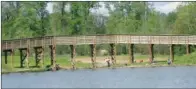  ??  ?? One of two bridges that span the creek that runs through the Cabot Community Fishing Pond provides the backdrop for a handful of anglers wetting a hook at the pond. The bridge, a paved exercise trail, lights, a pavilion, a playground and restrooms are...