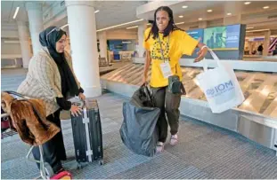  ?? AP PHOTO/ERIK VERDUZCO ?? Congo refugee Aline Mugabekazi, right, with Lutheran Services Carolinas case manager Raja Alshuaibi, retrieves her bag Wednesday at the airport in Columbia, S.C.