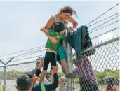  ?? SUZANNE CORDEIRO/GETTY-AFP ?? A mother helps her son over a U.s.-mexico border fence Aug. 25 in Eagle Pass, Texas.