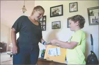  ?? BEA AHBECK/NEWS-SENTINEL ?? Rebecca Lovato and her son Matthew Gress, 9, check out a package he received at the family’s Lockeford home on Friday.
