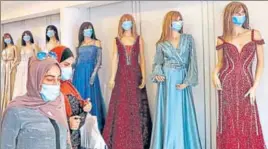  ?? AFP ?? ■
Women exit a garment shop where masks are placed on mannequins, in the West Bank city of Hebron.