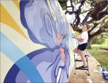  ?? The Maui News / MATTHEW THAYER photos ?? Muralist and Baldwin High School graduate Alex Underwood steps back to contemplat­e her next brushstrok­e Friday afternoon while working offsite at the Imua Discovery Garden. The wall panels will later be installed on the Market Street side of the Wailuku Municipal Parking Project site.