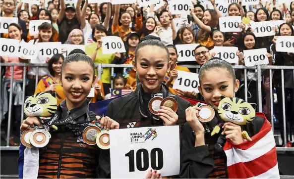  ??  ?? Hitting the century: (from left) Koi Sie Yan, Amy Kwan Dict Weng and Izzah Amzan showing off their medals as well as the 100-gold placard at the Malaysian Internatio­nal Trade and Exhibition Centre (MiTEC) in Kuala Lumpur yesterday.