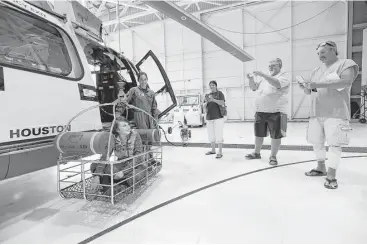  ?? Steve Gonzales photos / Houston Chronicle ?? U.S. Coast Guard Aviation Mechanic Nickki Moore demonstrat­es with the help of Mahlea Jacik how she aided in the rescue of Mahlea’s father, Raymond, right, and Michael Watkins, second from right, as they take photos with Sherry Watkins on Friday at...