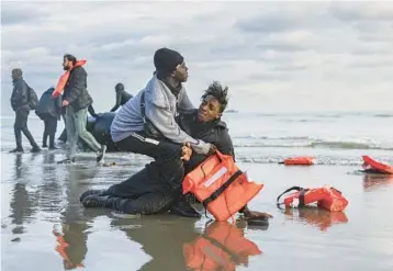  ?? SAMEER AL-DOUMY/GETTY-AFP ?? Departure thwarted: Sudanese migrants try to collect themselves Friday on the beach at Gravelines, near Dunkirk, in northern France after police punctured their smuggler’s boat to prevent the group from attempting to cross the English Channel to Britain. Earlier this week, Britain passed a controvers­ial bill to deport asylum seekers to Rwanda.