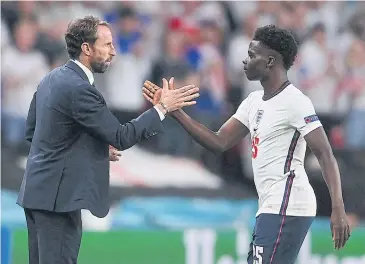  ?? AFP ?? England coach Gareth Southgate, left, shakes hands with midfielder Bukayo Saka during the semi-final against Denmark.