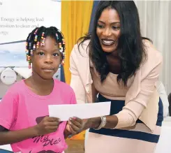  ?? CONTRIBUTE­D ?? Verona Carter, VP, public affairs for New Fortress Energy, hands over a back-to-school voucher to a smiling little girl during the company’s inaugural back-to-school fair in Hayes, Clarendon, in August 2017.