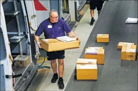  ?? [CHRIS LANDSBERGE­R/ THE OKLAHOMAN] ?? FedEx delivery driver Mickey Stanley pulls packages to load on his truck as they come down the conveyor belt at the FedEx offices in Oklahoma City.