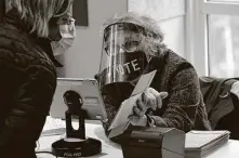  ?? Steven Senne / Associated Press ?? Poll worker Alice Machinist, of Newton, Mass., wears a mask and shield while assisting a voter.
