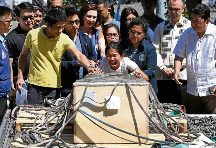  ?? —LYN RILLON ?? GRIM REUNION As government officials look on, Jessica Demafelis weeps while hugging the sealed casket of her sister, Joanna, whose remains were flown in from Kuwait on Friday morning. Joanna, whowas reported missing for a year, was found inside a...