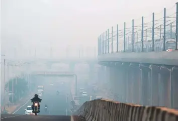  ?? Bloomberg ?? Vehicles travelling along a road that is shrouded in smog in Delhi. The smog has been caused by seasonal burning of crop stubble and emissions from vehicles and industry.