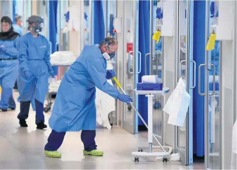  ??  ?? Crisis management: staff wearing PPE cleaning a hospital ward, and (below), a nurse in personal protection equipment on a ward