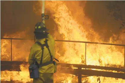  ?? Jeff Chiu / Associated Press ?? Left: A firefighte­r battles flames Monday at Keysight Technologi­es in Santa Rosa. The company said most of its headquarte­rs are intact, but some workers lost homes.